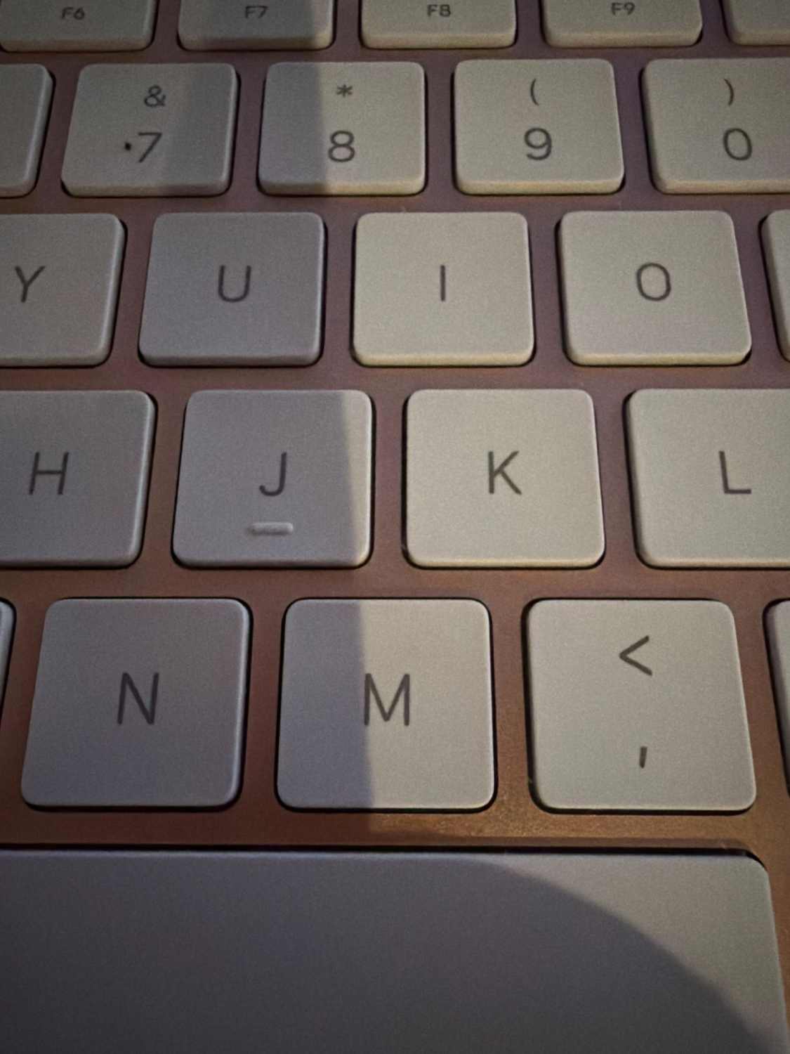 Side view of the Apple keyboard on a wooden surface.