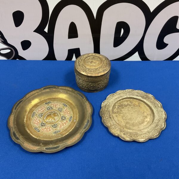 Vintage brass plates and pot with intricate floral designs.