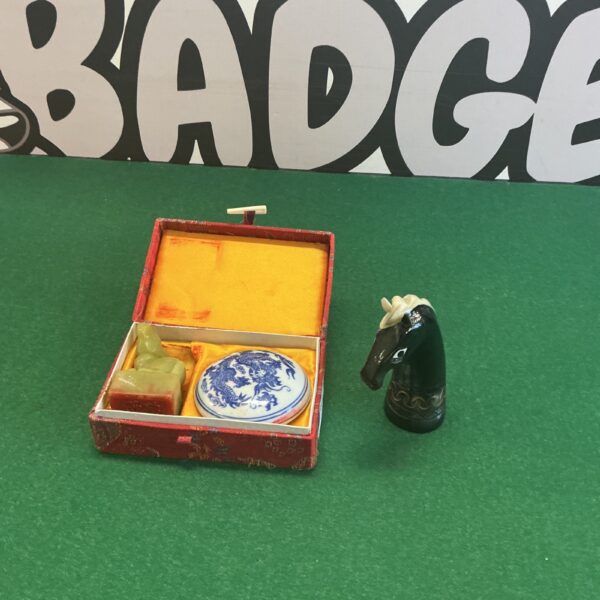 Chinese trinket box and miniature horn set on green surface.