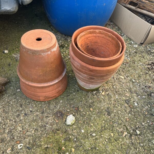 Two terracotta clay plant pots in a garden setting.