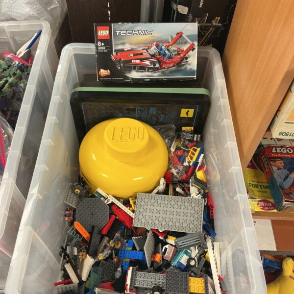 Mixed lot of Lego sets and pieces in a clear storage box.