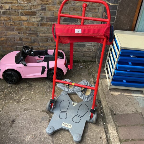 Red moving trolley with two wheels for transporting goods.