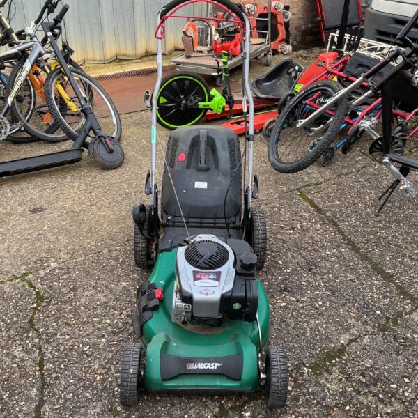Vintage Qualcast 625 EX petrol lawnmower in a garden setting.