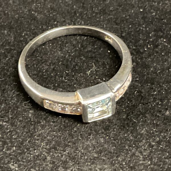 Close-up of a silver ring with a rectangular topaz stone.