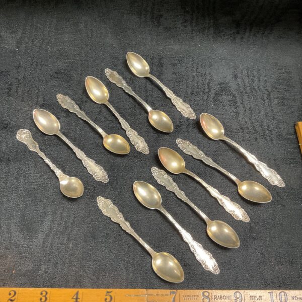 Eleven antique sterling silver teaspoons with floral engraving.