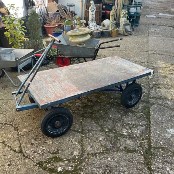 Vintage garden cart with wooden platform and metal wheels.