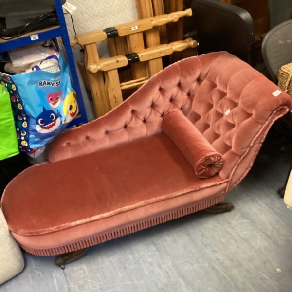 Vintage pink chaise lounge with button tufting and wooden legs.